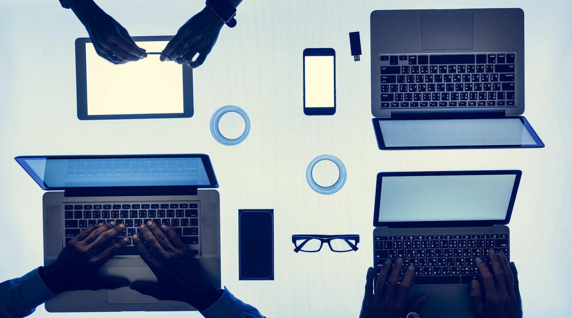 computers and smartphnes on backlit table